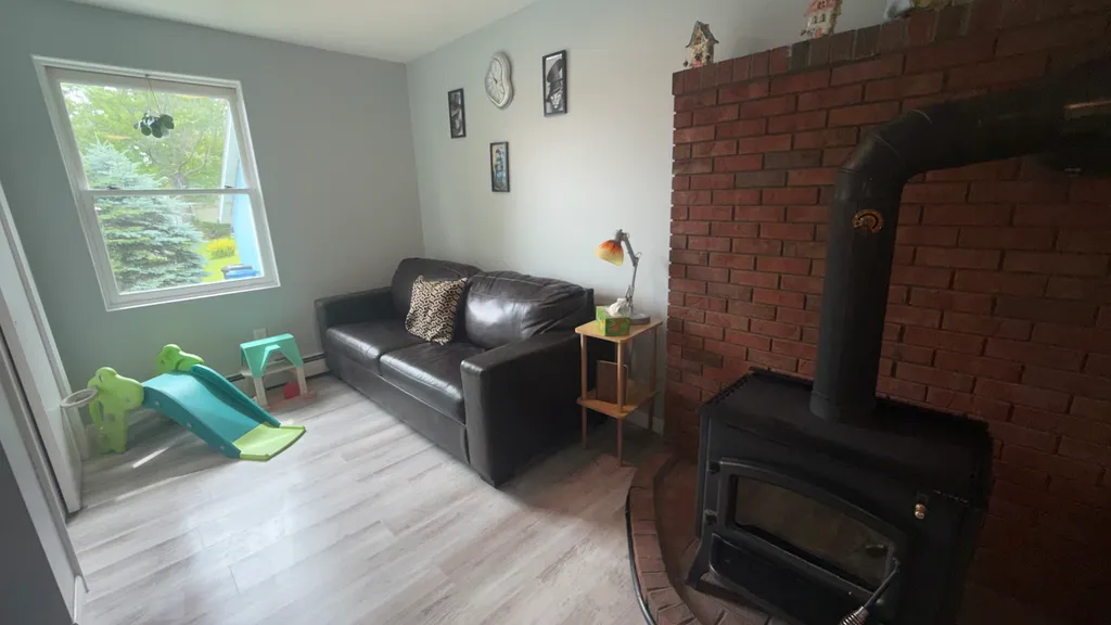 A living room with a black couch, brick fireplace, and a small play slide.