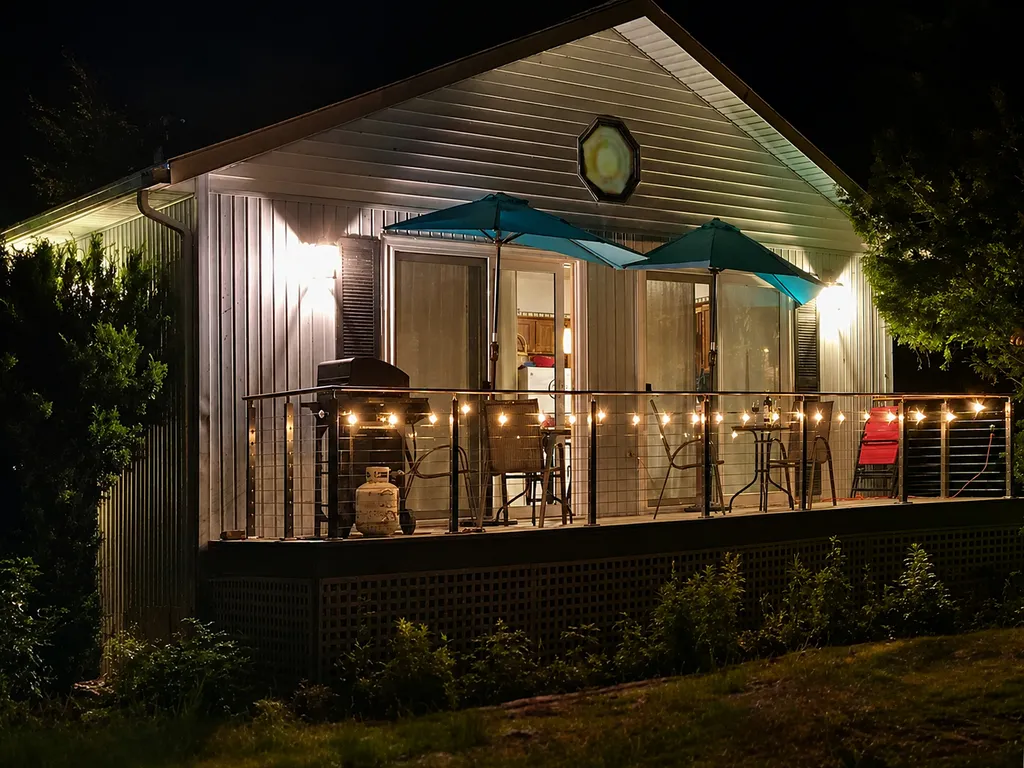 A cozy cabin with a porch, string lights, and two umbrellas.