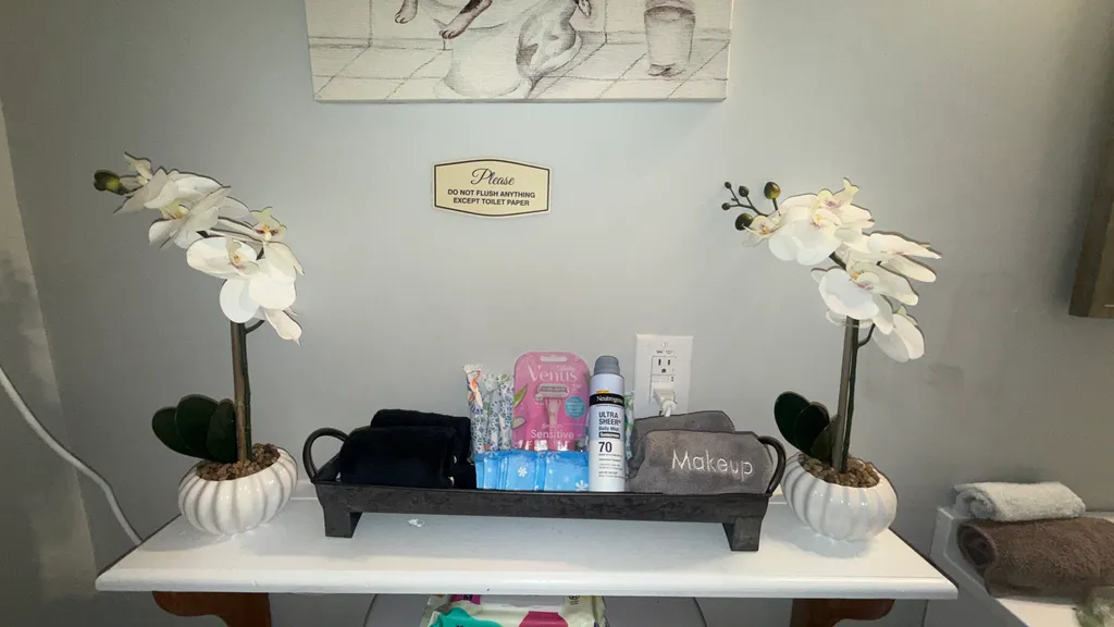 A white table with a tray of toiletries and two white orchids in vases.
