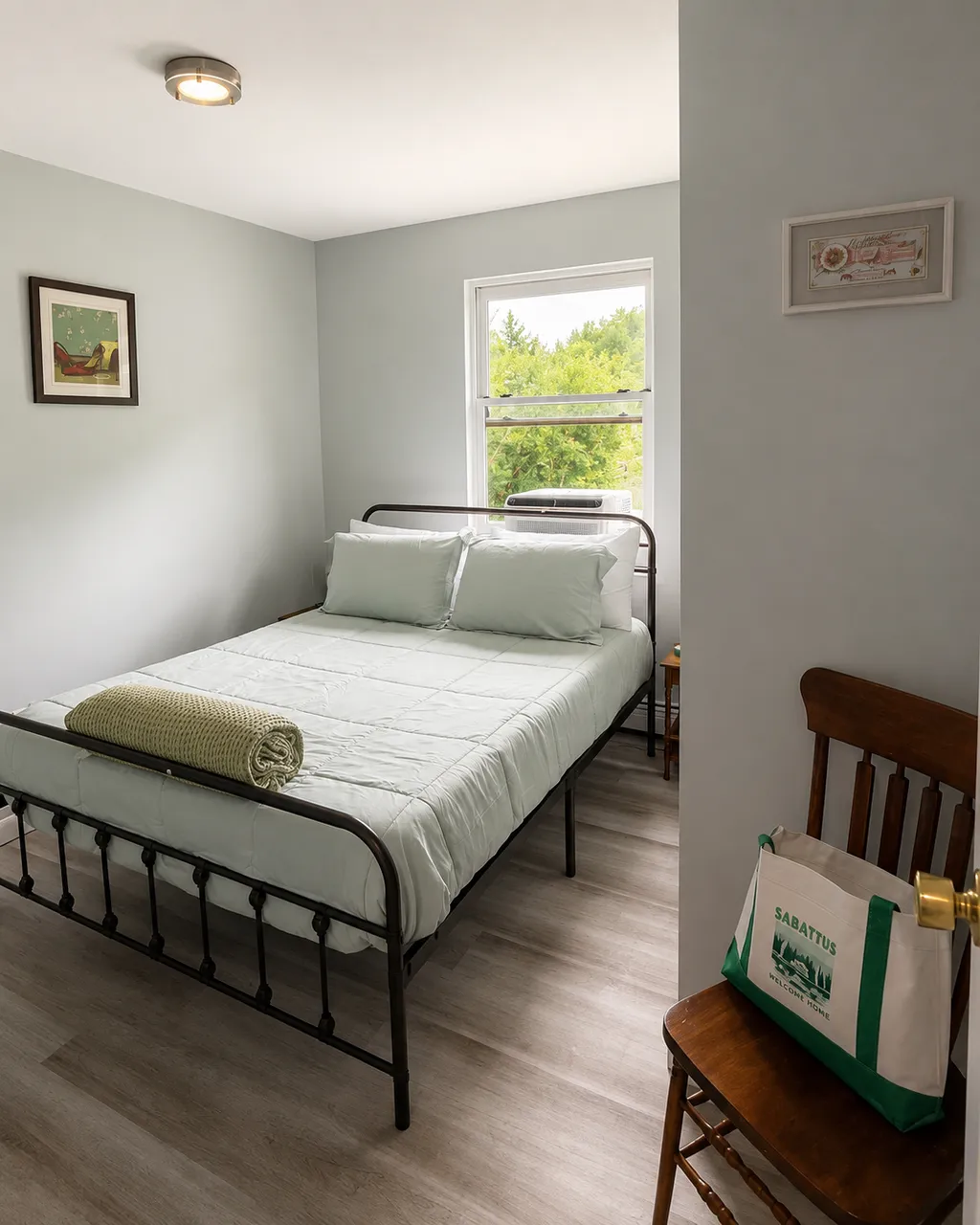 A bedroom with a bed, pillows, and a chair with a bag.