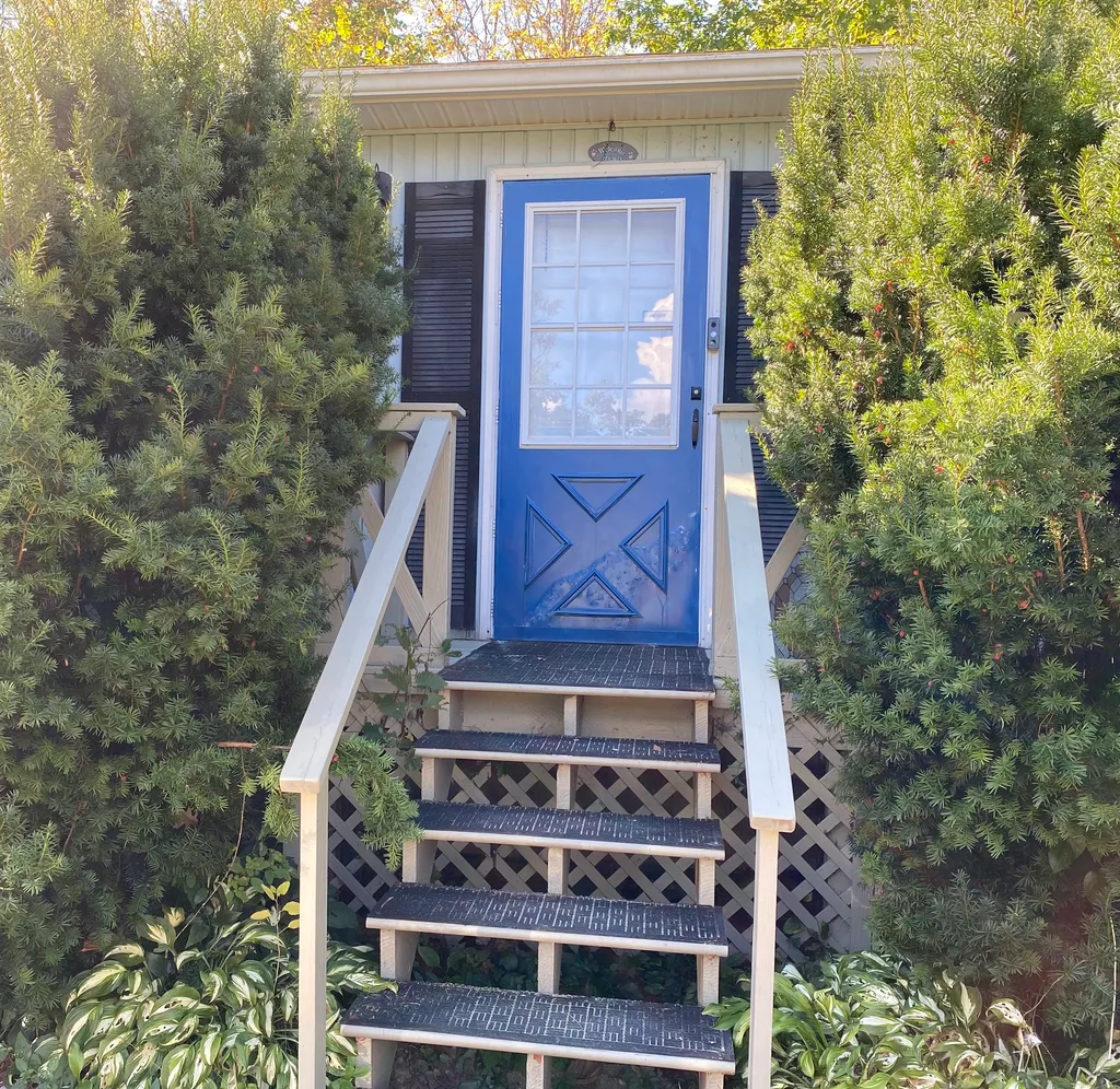 A small house with a blue door and white railings.
