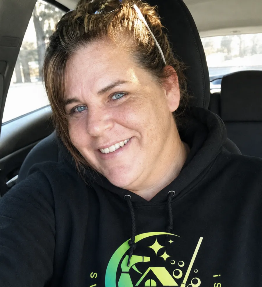 Woman in a car wearing a black hoodie with a green logo.